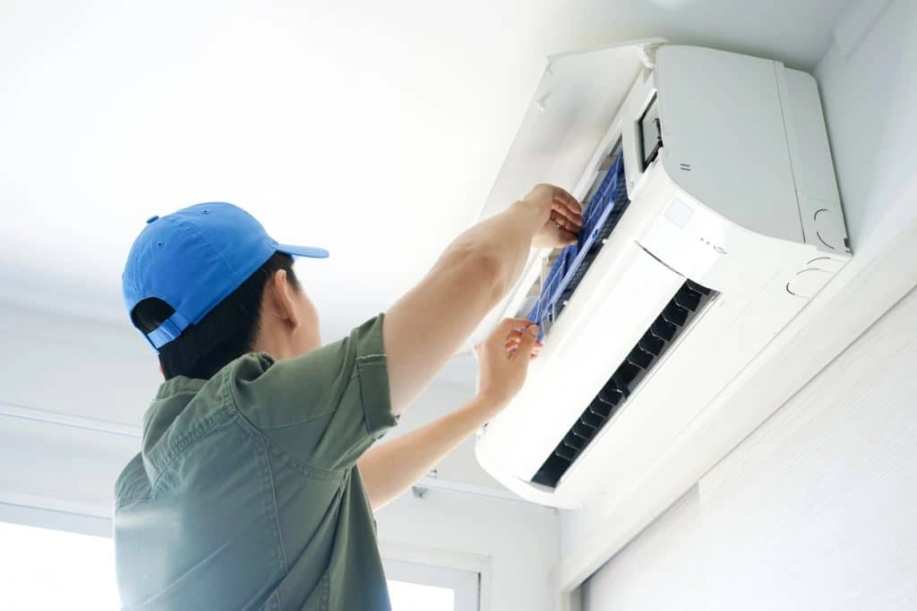 Technician checking the filter of an indoor wall-mounted air conditioner