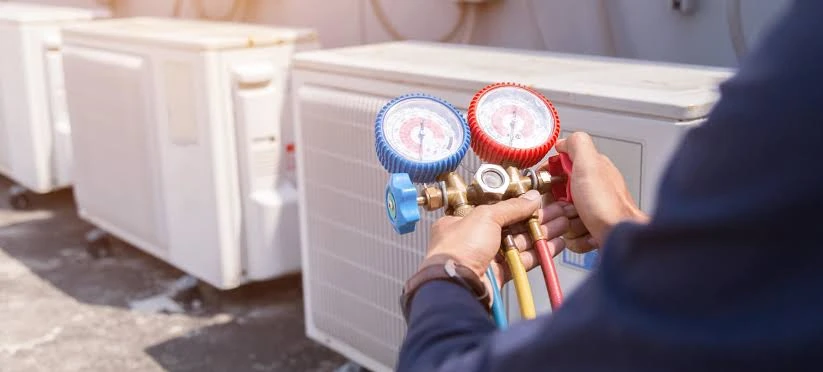 Technician checking air conditioner pressure with manifold gauges