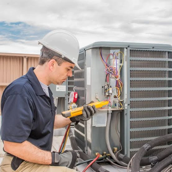 Technician checking electrical components of an outdoor HVAC unit
